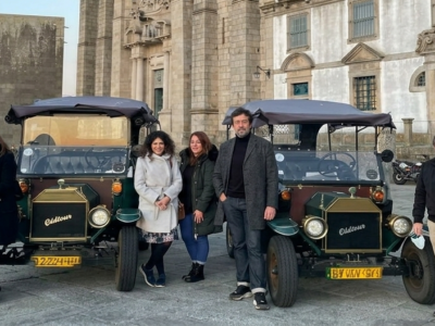 Grupo de viajeros junto a coches clásicos vintage durante un tour privado por el centro histórico de Oporto