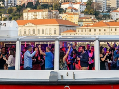 Grupo de personas disfrutando de una fiesta en barco por el río Duero con música y bebidas en Oporto