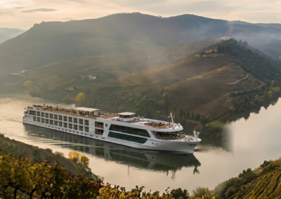 Barco navegando por el Valle del Duero rodeado de viñedos en terrazas y montañas en Portugal