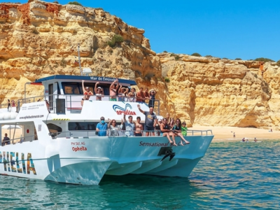 Catamarán con turistas navegando frente a los acantilados de Benagil en el Algarve.