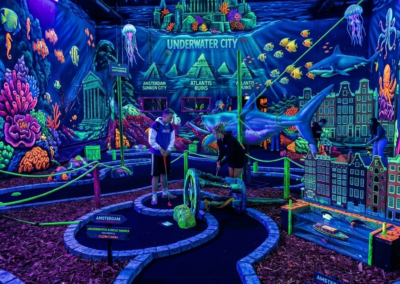 Personas jugando mini golf fluorescente en Ámsterdam con temática submarina y ciudad acuática