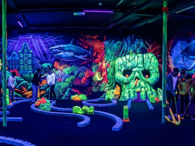 Personas jugando mini golf fluorescente en Ámsterdam con temática de piratas y océano