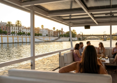 Interior de la zona de relax de un barco privado en Sevilla con vistas panorámicas al barrio de Triana y al río.