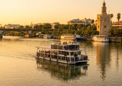 Barco privado para eventos navegando por el Guadalquivir con el skyline de Sevilla y el Puente de Triana al atardecer.