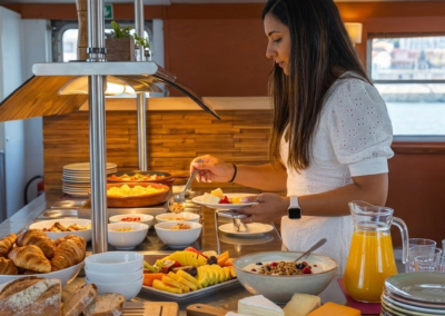 Persona sirviéndose comida en un buffet de brunch durante un crucero por el río Tajo en Lisboa.