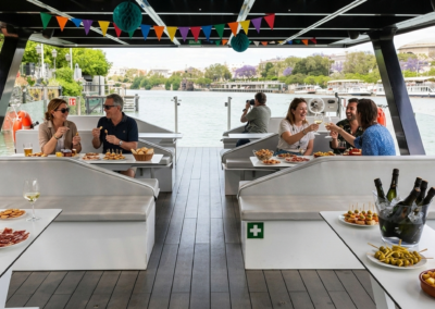 Grupo de personas comiendo tapas y brindando a bordo de un barco privado navegando por el río Guadalquivir en Sevilla