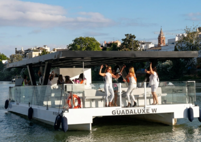 Personas bailando y celebrando en un barco privado navegando por el río Guadalquivir en Sevilla