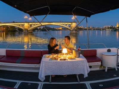 Pareja disfrutando de una cena romántica en un barco privado por el río Guadalquivir en Sevilla.
