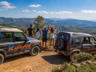 Vehículos 4x4 de aventura con viajeros disfrutando de vistas panorámicas en una ruta off road por la montaña.